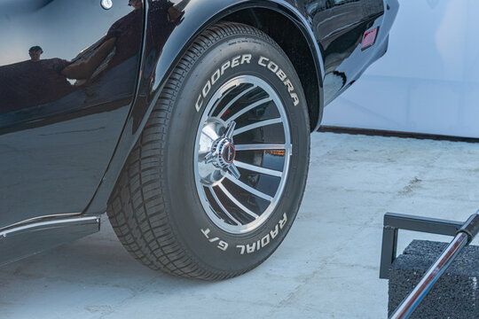 Black Dodge Charger with alloy wheels, glossy finish, red center caps on alloy wheels, Pirelli tire brand, chrome grille accents, bright outdoor lighting, side view  Kyiv, Ukraine September 21, 2025