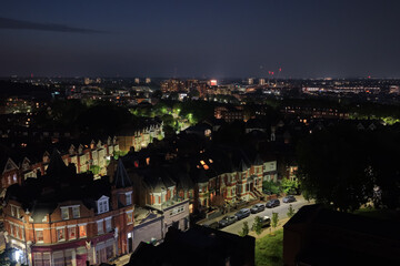 Obraz premium Aerial night view of Hornsey, North London residential neighbourhood with illuminated cityscape and urban skyline, drone photography