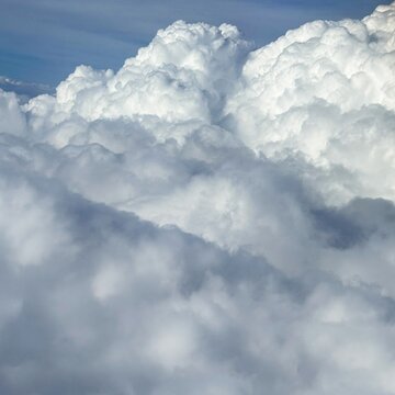 Bright white cumulus clouds fill the sky above a soft haze layer, creating a calm airy mood, ideal for weather themes and serene nature backgrounds