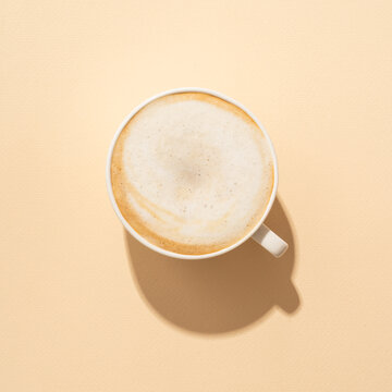 Coffee cup cappuccino foam at colored background with hard shadow.