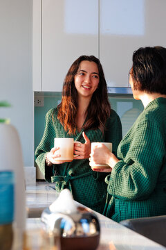 Mother and daughter enjoying morning coffee in matching robes