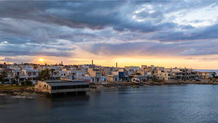 Fototapeta premium Sunset over a city in Apulia, view of the city from the sea. Italy, Apulia, Salento