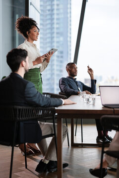 Businesswoman presents to colleagues in modern office setting.