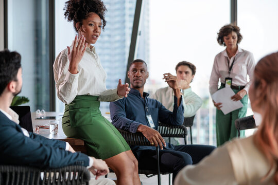 Businesswoman leads meeting with diverse colleagues in modern office.