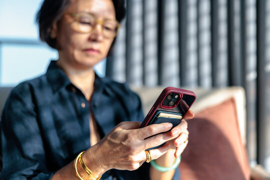Woman with glasses using smartphone with card holder case.