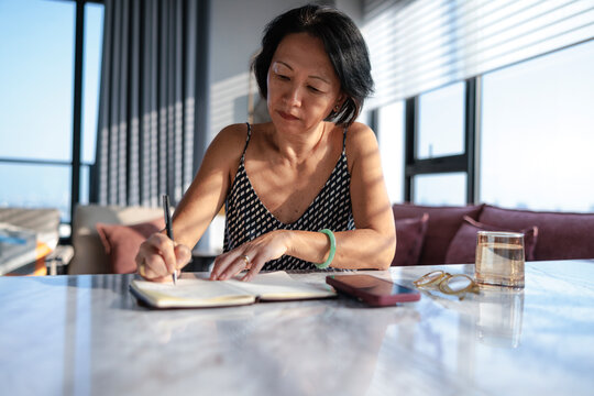 Woman writing in notebook by window