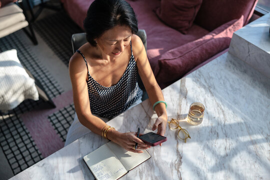 Woman with phone and notebook at marble table.