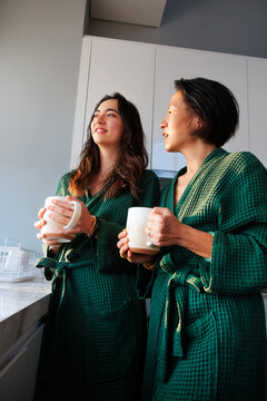 Mother and daughter enjoying coffee together in matching robes