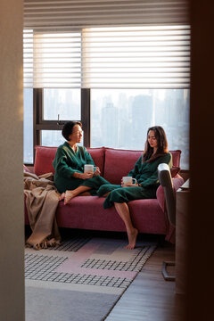 Mother and daughter enjoying coffee together with city view at home