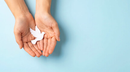 White paper dove in cupped hands, symbolic peace bird on light blue background, concept of hope and harmony, minimalist spiritual freedom imagery