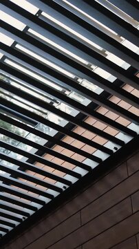 Vertical video. Close-up of slatted roof above modern house terrace against natural surroundings.
