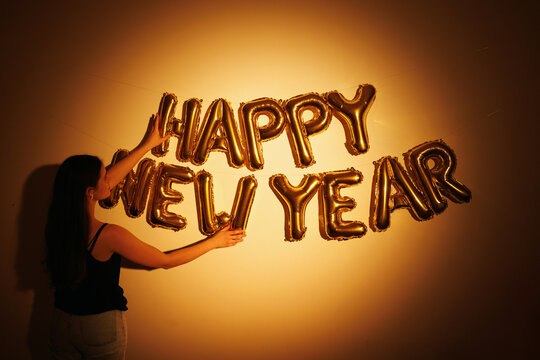 Woman Celebrates with Gold Happy New Year Balloons