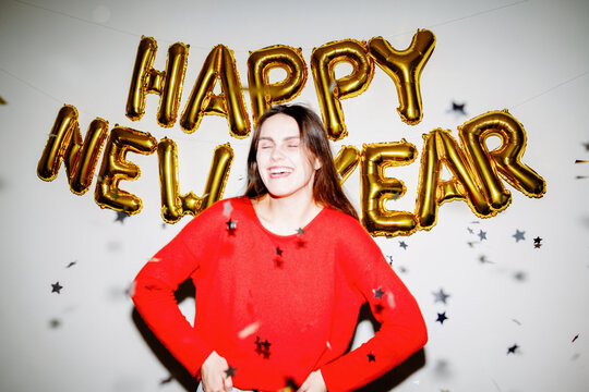 Woman celebrating with Happy New Year balloons with flash