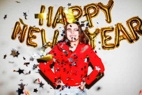 Woman in red sweater with confetti and happy new year balloons