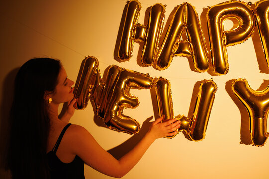 Woman arranging gold happy new year balloons