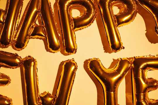 Gold happy new year balloons on beige wall