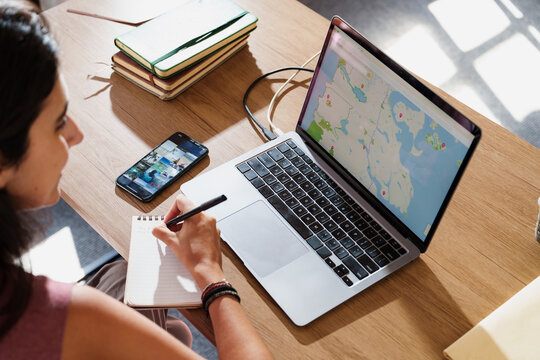 Woman Planning Trip with Laptop and Smartphone at Home