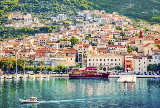 Aerial view Colorful waterfront of Makarska on the Adriatic Sea, Croatia. Sailboats and a red yacht in the marina below Biokovo mountains&mdash;sunny summer travel destination