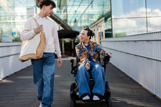Companion walking with woman in power wheelchair