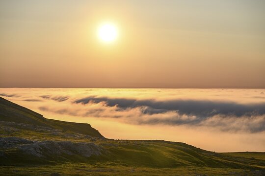 View from Mount Domen. Dense sea fog hangs over the Barents Sea the midnight sun shines in the north in an orange sky, Domen, Vard&ouml;, Finnmark, Norway