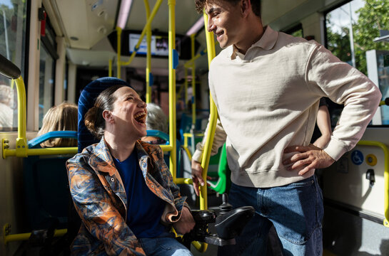 Joyful disabled woman laughing with friend on public bus