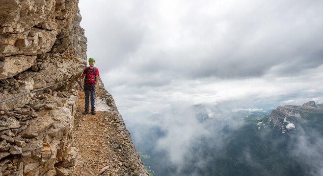 Young man, hiker secured to a steel rope climbing a rock face, Via Ferrata Francesco Berti, Sorapiss circumnavigation, Dolomites, Belluno, Italy