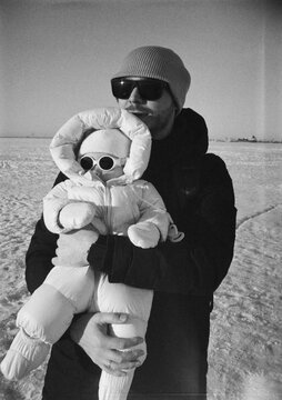 Man holds baby in winter clothing on a snowy day