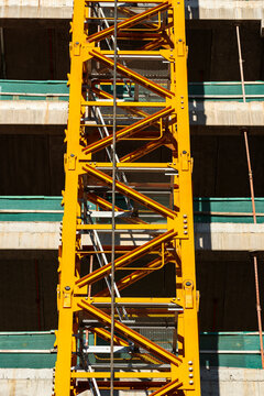 Rhythmic crane structure rising across concrete facade