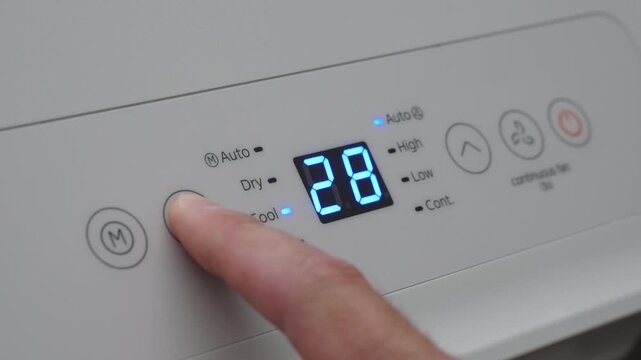 Turning Down Temperature on Thermostat in Summer in Hot Weather. Setting Digital Home Thermostat to Cool and Programming Air Conditioner. Adjusting Room Temperature to Energy Saving in Summer Heat.