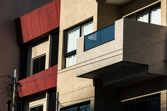 Angular beige facade with red bands and balcony volume