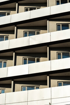 Repetitive balcony bands across sunlit residential facade