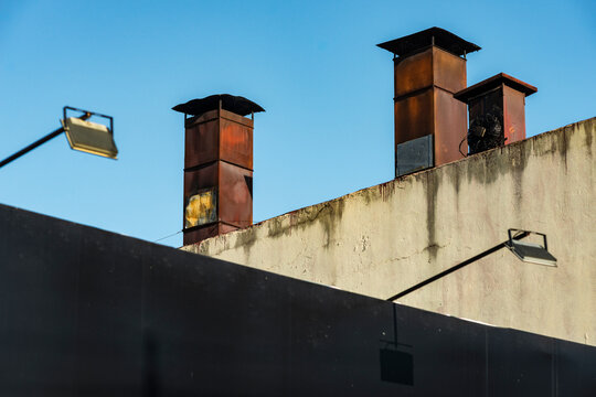 Rusted chimney forms above angled rooftop wall
