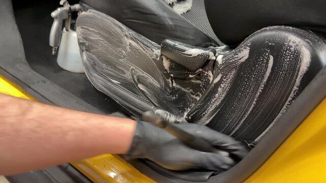 The process of professional detailing dry cleaning of the interior of the car using chemistry and tornado air gun. The detailing master cleans the car interior with a hot steam cleaner, brush. 
