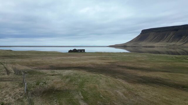 Survol d'un lac avec les ruines d'une maison et une montagne plate