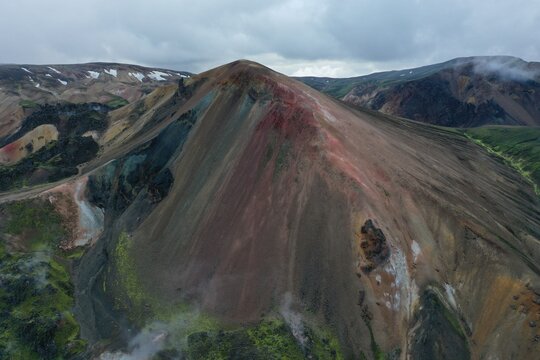 Aerial view of the colorful rhyolite mountains of Kerlingarfjoll with geothermal steam vents and vibrant mossy slopes in the highlands of Hella, Rangarthing ytra, Iceland.
