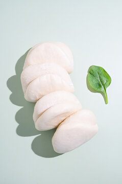 Plain white steamed bao buns isolated on a clean light background with shadows.