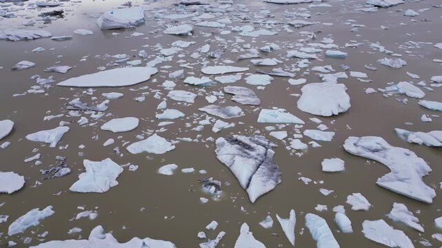 survol de centaines de morceaux de glace recouvrent les eaux marrons d'un lac glaciaire