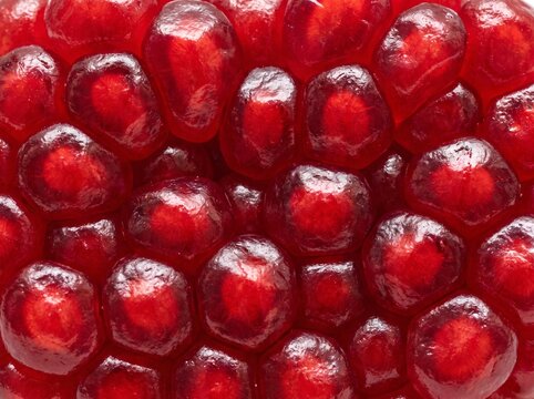 Closeup of fresh ripe pomegranate seeds, vibrant red fruit arils texture background