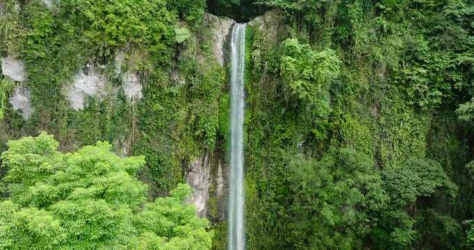 Waterfall with cold water surrounded by green trees in Camiguin Island. Katibawasan Falls. Philippines.
