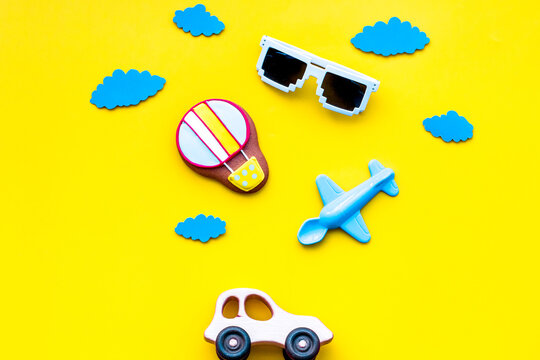 Airplan, car and air balloon toys for family traveling with child on yellow background top view mock-up