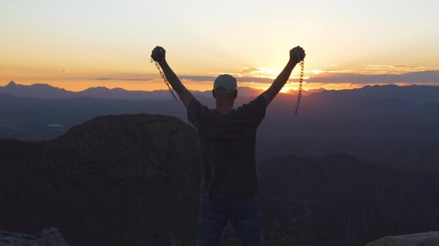 A man thankful to be free from chains at sunset