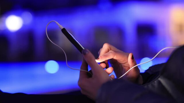 Woman using smartphone by pool at night &ndash; glowing screen, copy space, modern lifestyle.