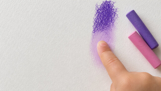 Child's finger smudging purple chalk on white paper, purple and pink chalk sticks in corner, creative art activity, blending technique, childhood education and sensory play.