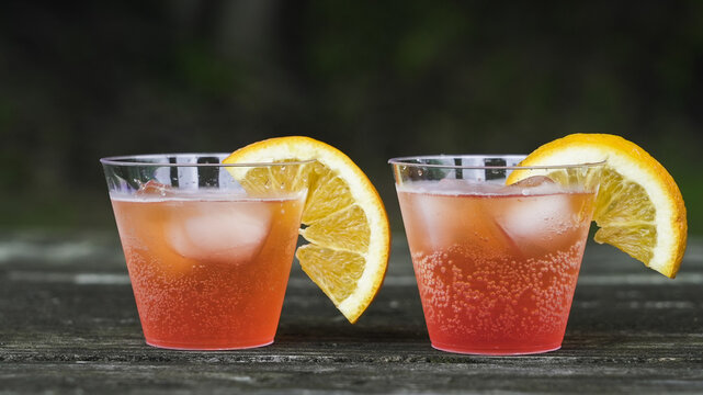 Refreshing cocktails with orange slices on wooden table