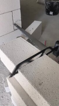 Electric reciprocating saw with an aerated concrete blade cutting a gas concrete block. Close-up of a construction tool in action.