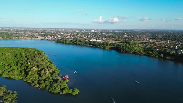 Cinematic establishing drone video showcasing the massive Ucayali River flowing through the lush rainforest with Yarinacocha district nesting in the distance.
