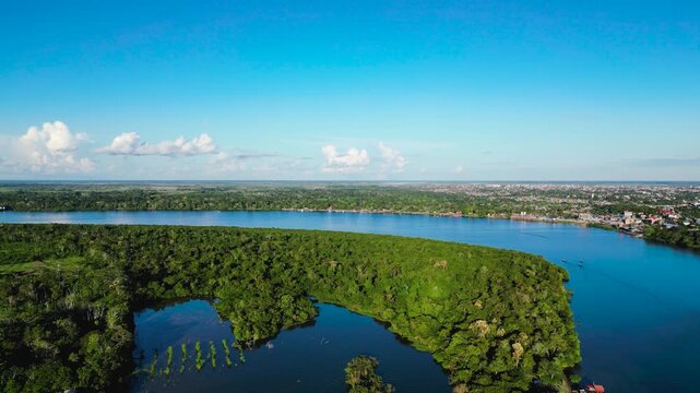 Breathtaking 4K drone point of view gliding above the immense Ucayali River in Pucallpa, toward the remote tropical horizon under a bright sunny blue sky.