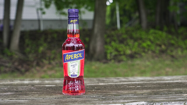 NORWALK, CT, USA - JUNE 26, 2026: Aperol bottle with orange liqueur on a wooden surface in an outdoor setting