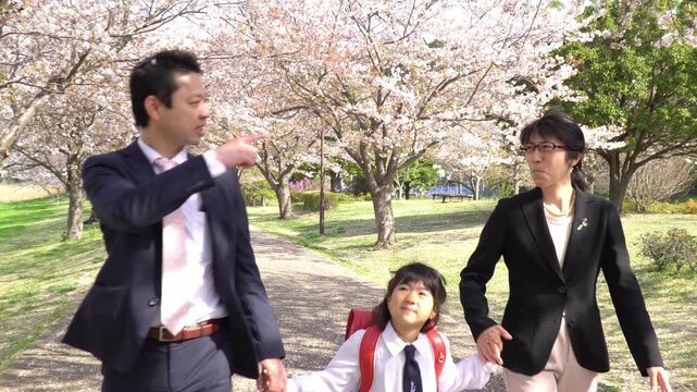 両親と手をつないで歩く小学一年生の女の子