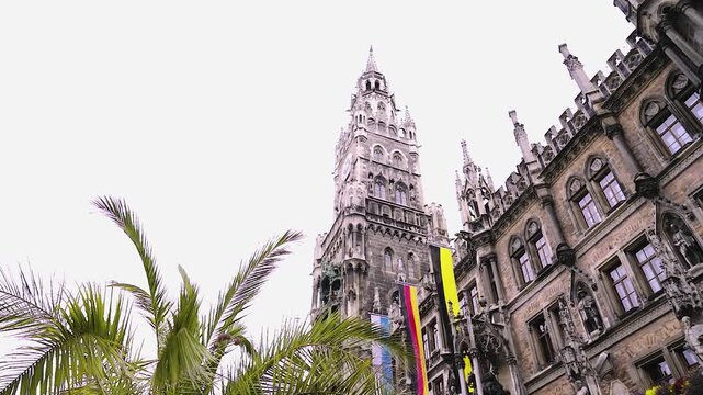 Neues Rathaus am Marienplatz mit Palme und Fahnen an einem Sommertag